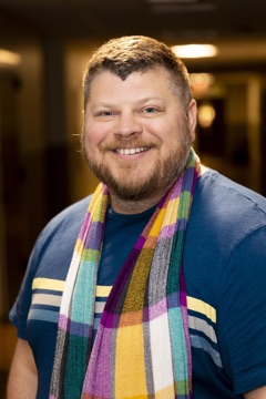 Matthew Kruger-Ross, smiling in a colorful plaid scarf